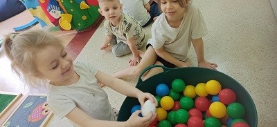 dzieci bawią się kolorowymi piłeczkami 