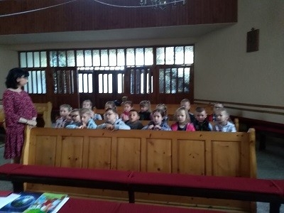 dzieci siedzą w ławce w kościele 