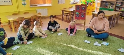 dzieci siedzą na dywanie z kopertami 