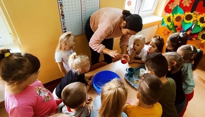 dzieci wraz z nauczycielką przygotowują ciastolinę 